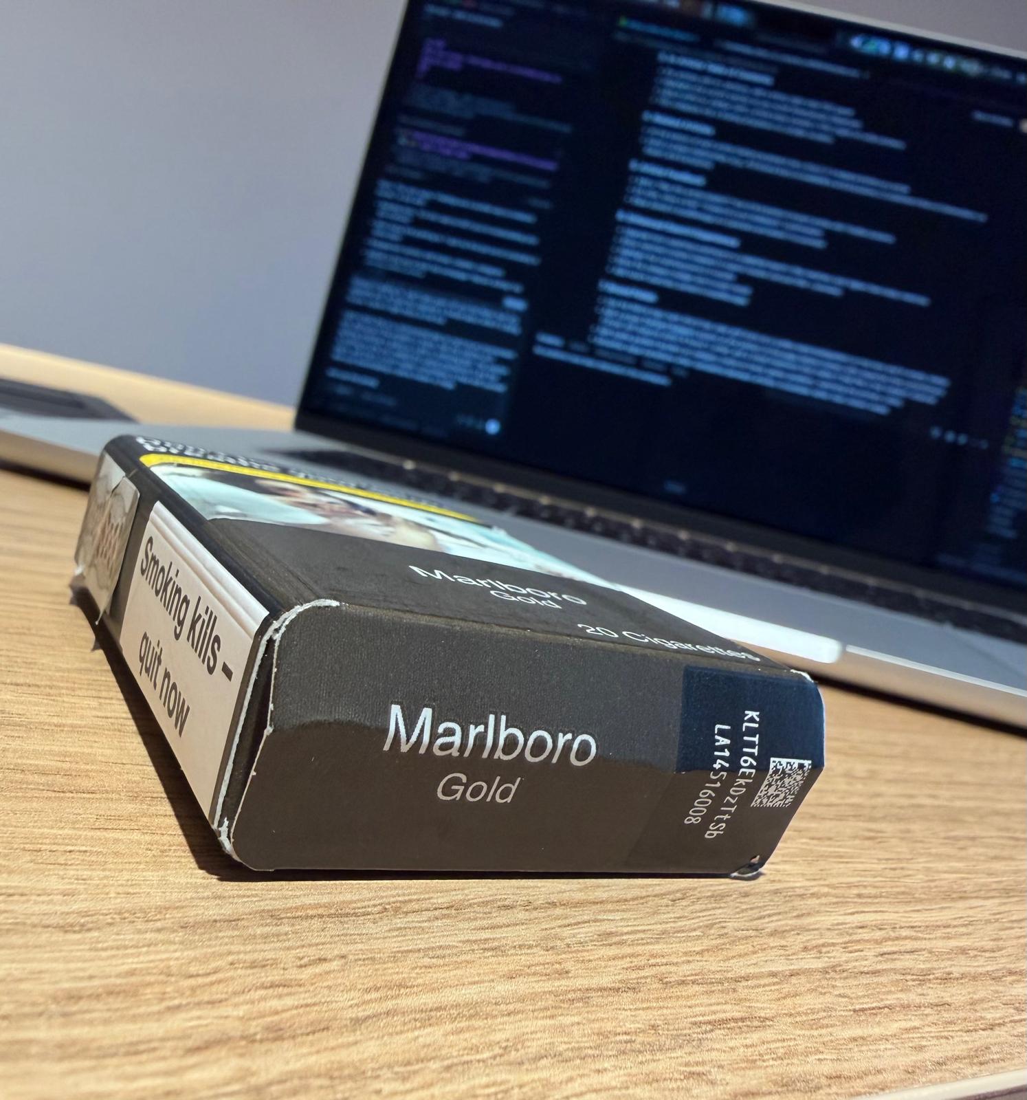 Marlboro Gold cigarette pack on a desk next to a laptop